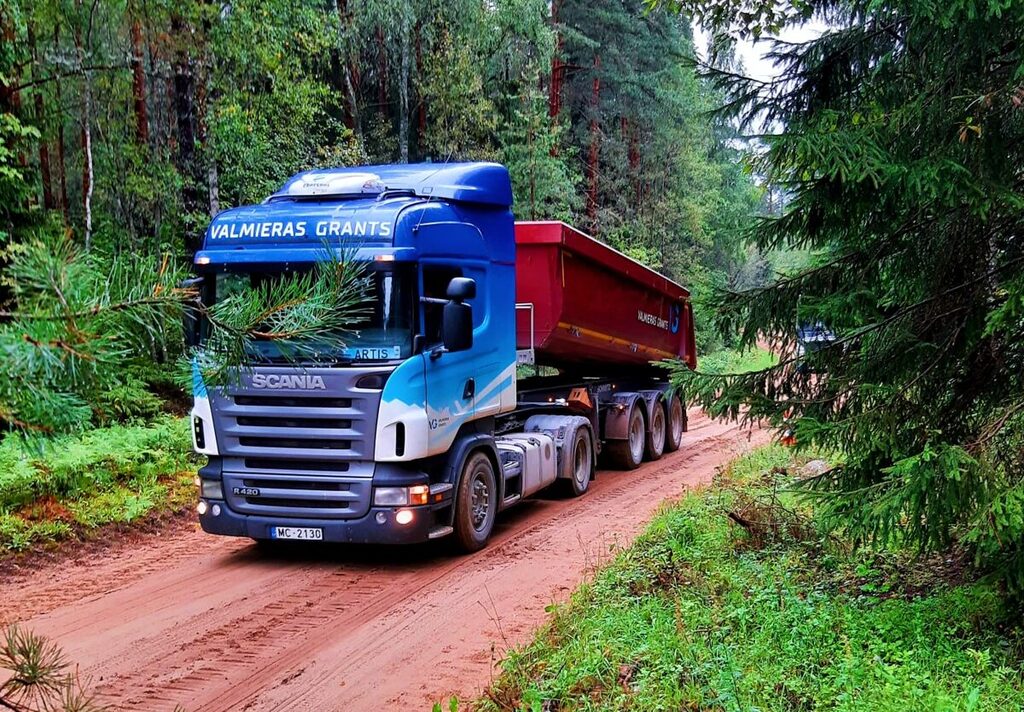 Scania kravas automašīna pārvadā grants pa meža ceļu