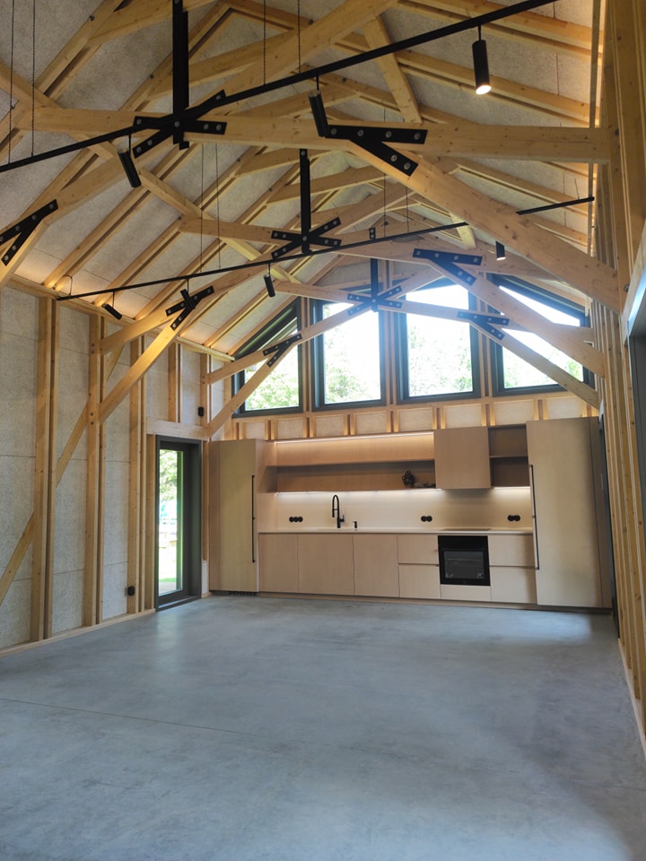 Moderns koka mājas interjers ar augstiem griestiem un sijām